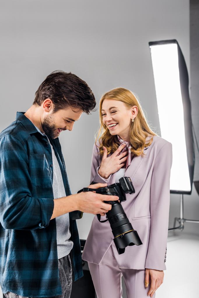 schöne junge Fotografin und lächelndes weibliches Model mit Fotokamera und lachend im Studio   - Foto, Bild