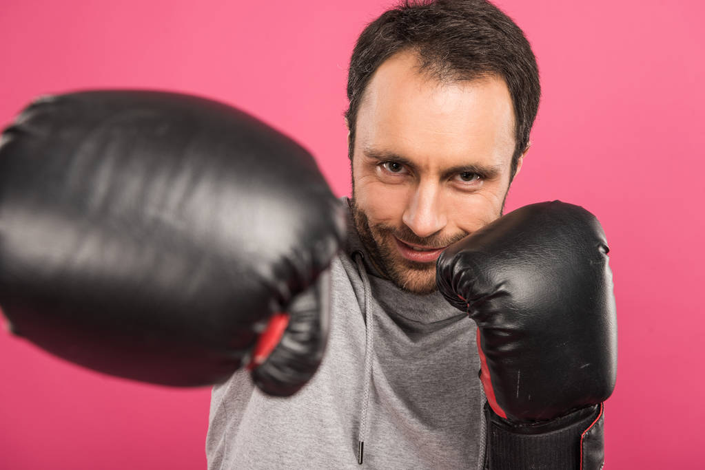 smiling sportive man training in box gloves, isolated on pink - Photo, Image