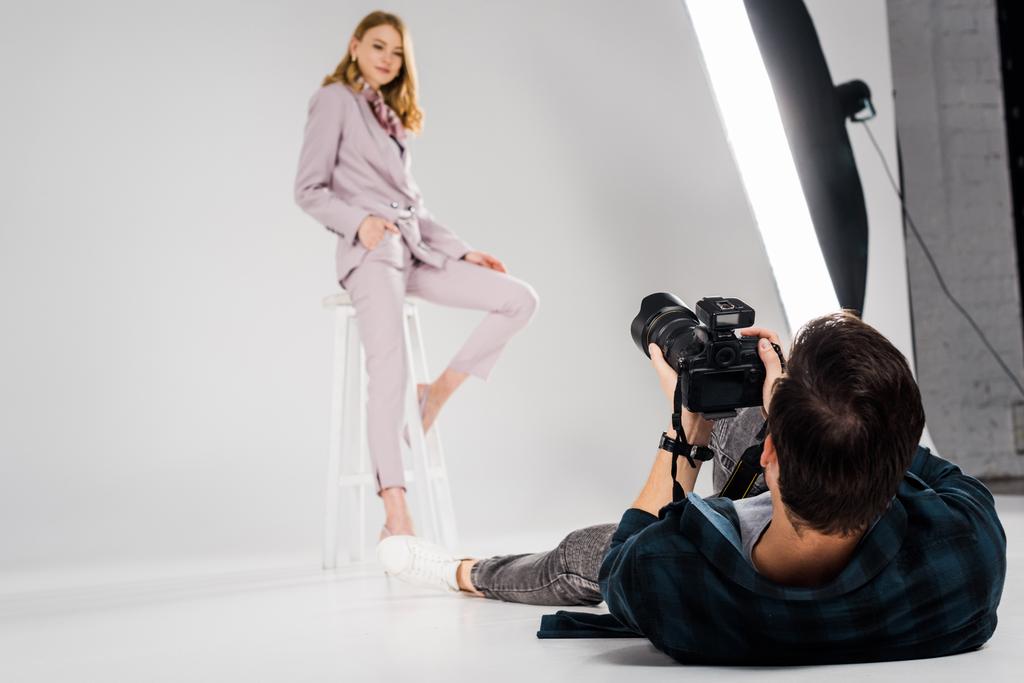 fotógrafo mintiendo y disparando hermosa modelo femenina posando en estudio
    - Foto, imagen