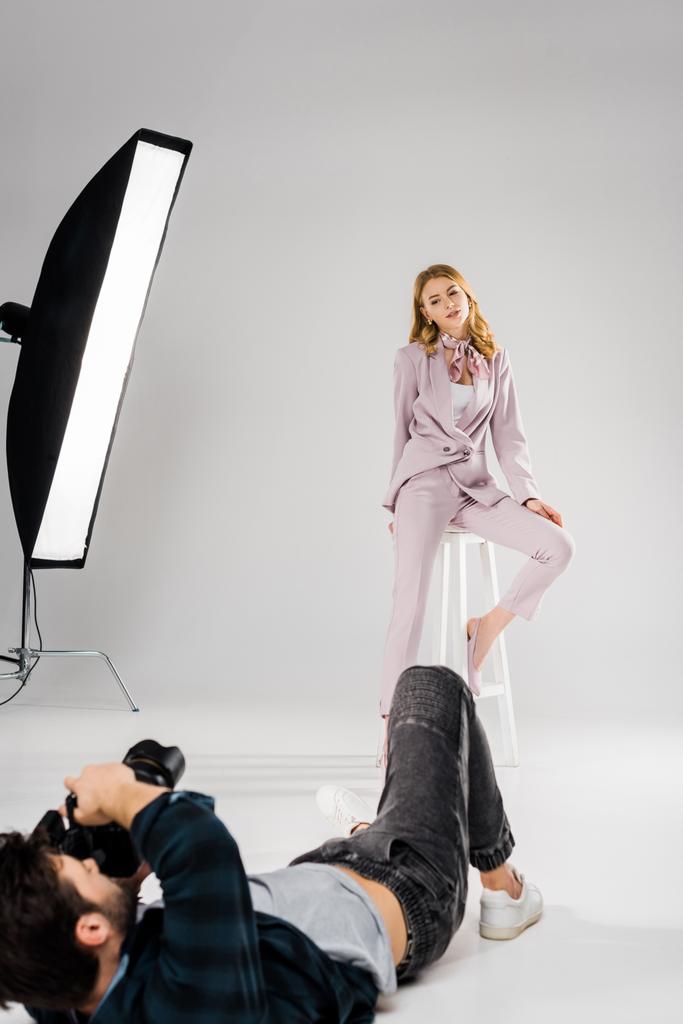 fotógrafa tumbada y fotografiando hermosa modelo femenina posando en estudio
   - Foto, imagen