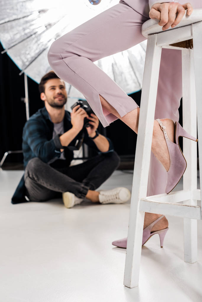 ritagliato colpo di fotografo sorridente seduto e fotografare elegante modello femminile in studio
   - Foto, immagini