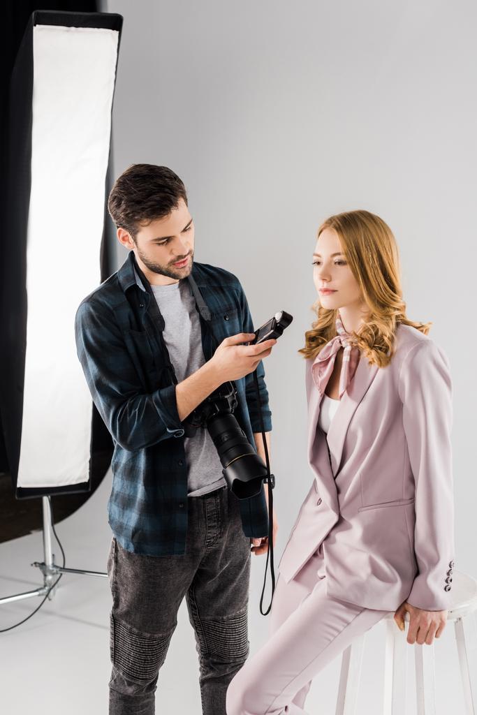 jeune photographe tenant un compteur de lumière et travaillant avec un modèle féminin dans un studio photo
 - Photo, image