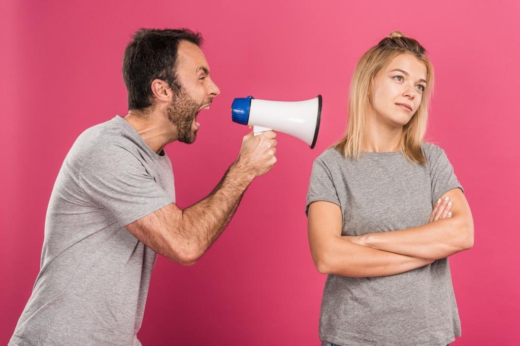 agresivní muž křičí s megafonem přítelkyně, izolované na růžová - Fotografie, Obrázek