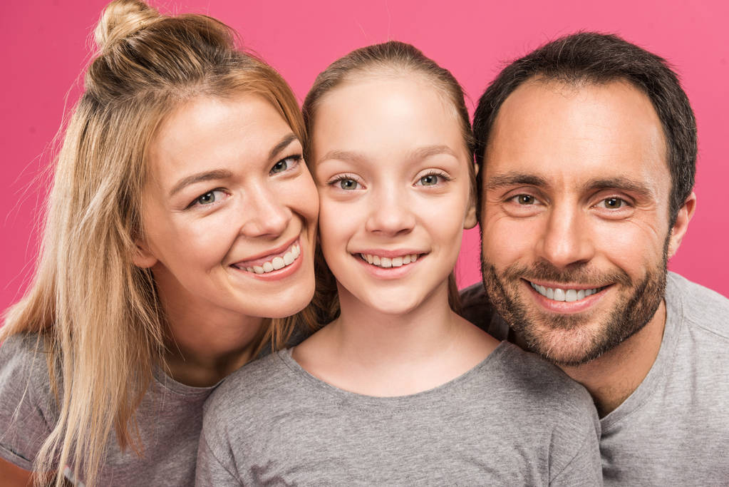 kaunis hymyilevä vanhemmat ja onnellinen tytär, eristetty vaaleanpunainen
 - Valokuva, kuva