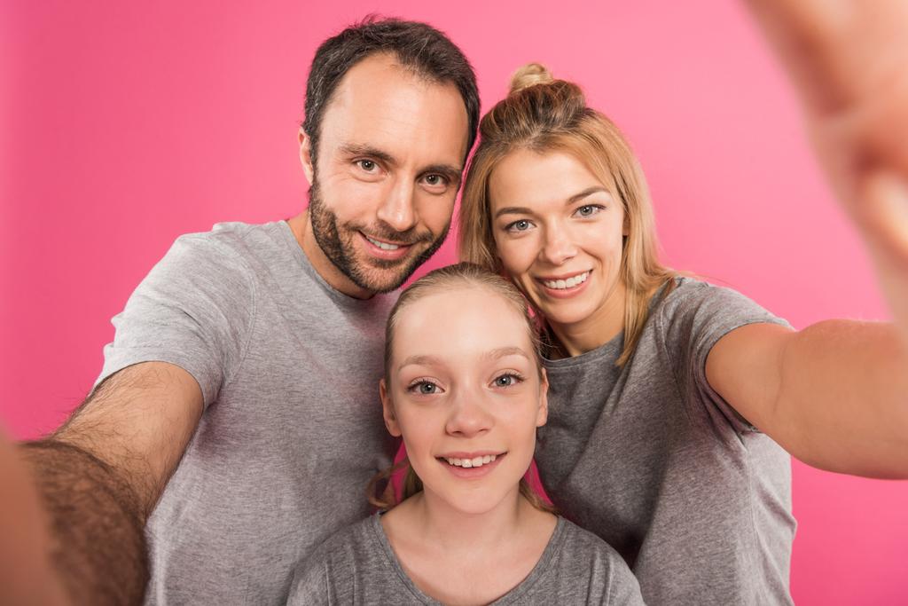 χαμογελώντας οικογένεια λήψη selfie μαζί, απομονώνονται σε ροζ - Φωτογραφία, εικόνα
