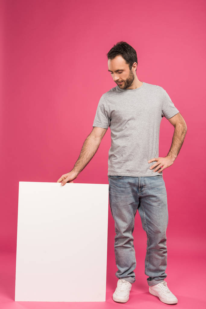 bonito homem de pé perto de placa em branco, isolado em rosa
 - Foto, Imagem