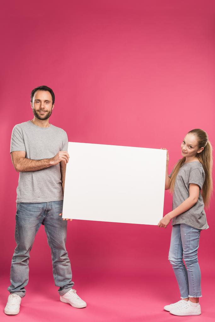 knappe vader en dochter poseren met lege bordje, geïsoleerd op roze - Foto, afbeelding