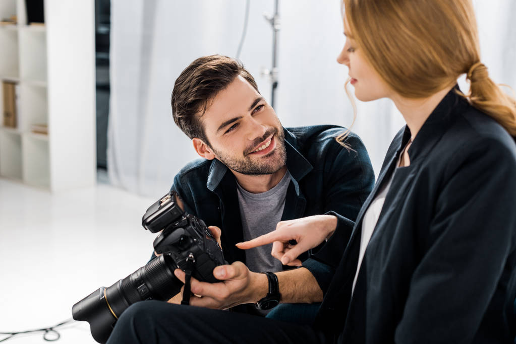 χαρούμενος νεαρός φωτογράφος και μοντέλο χρησιμοποιώντας φωτογραφική μαζί στο studio - Φωτογραφία, εικόνα