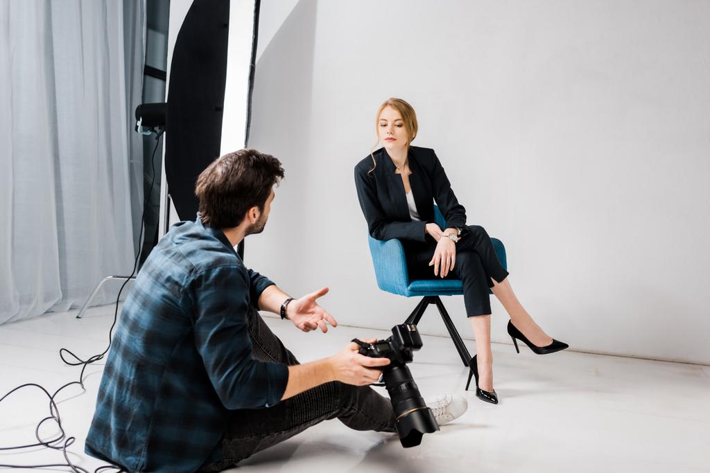 photographer with camera and young model talking in photo studio - Photo, Image