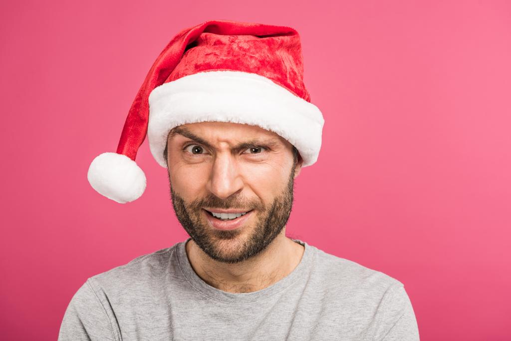 portrait of funny confused man in santa hat, isolated on pink - Photo, Image