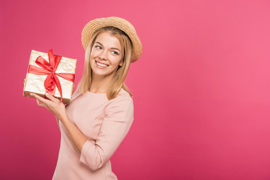 mooie lachende vrouw houden de doos van de gift geïsoleerd op roze  - Foto, afbeelding