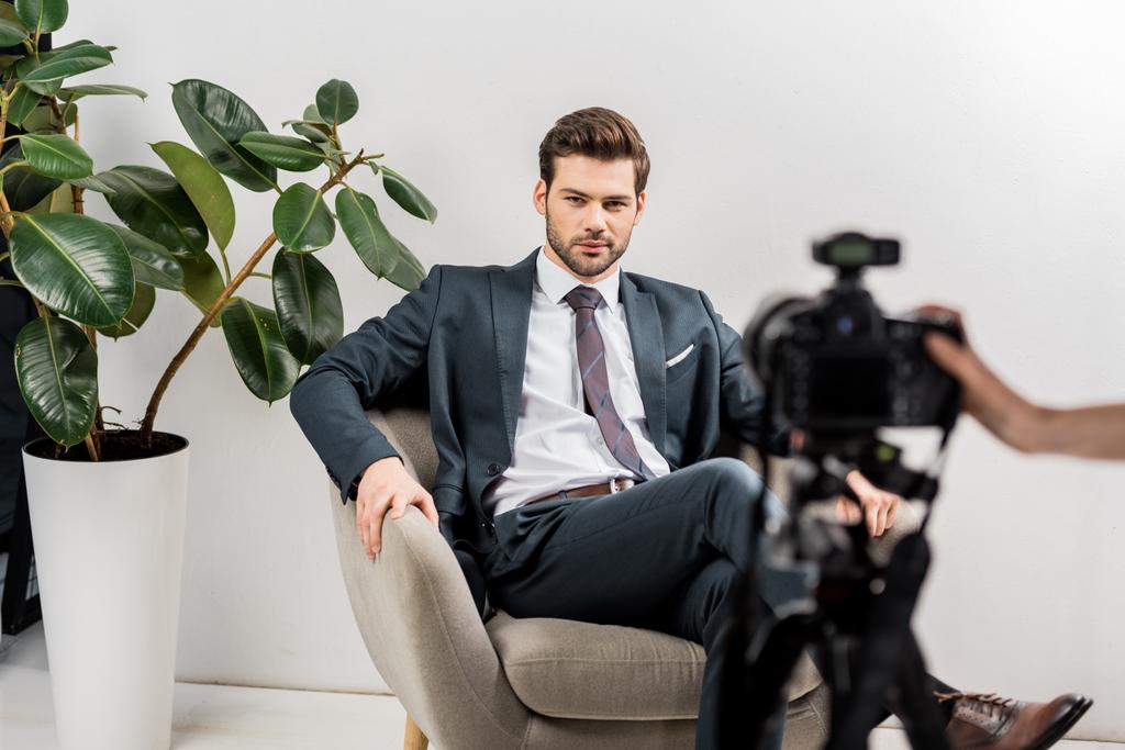 cropped shot of photographer taking pictures of handsome man in stylish suit in studio - Photo, Image