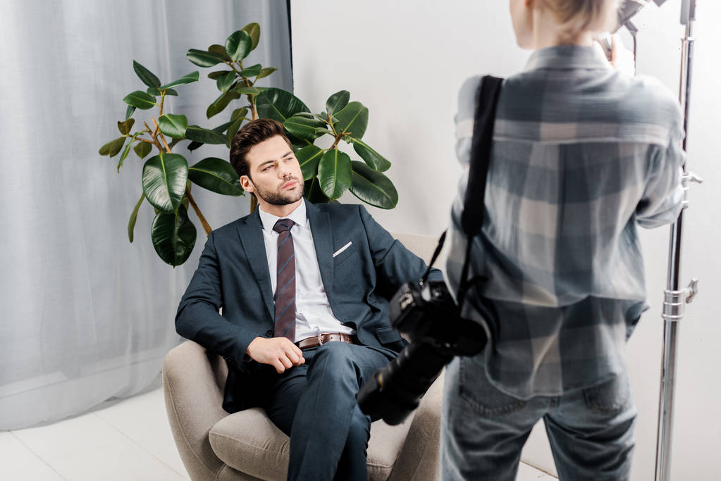 vista posterior del fotógrafo con cámara mirando apuesto hombre de negocios en el estudio de fotografía
 - Foto, imagen