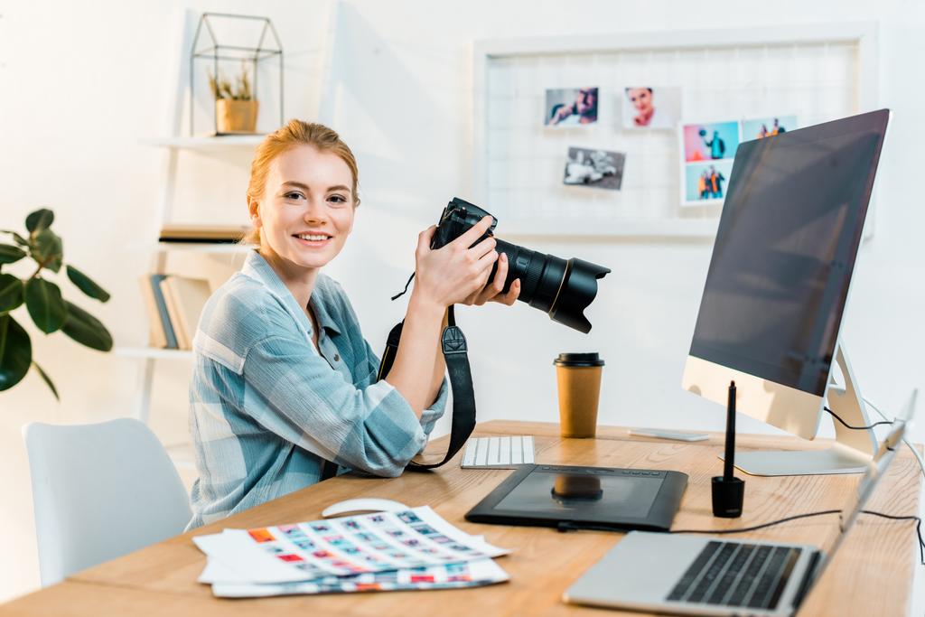 office で作業しながらカメラに笑顔美しい若い女性写真家 - 写真・画像