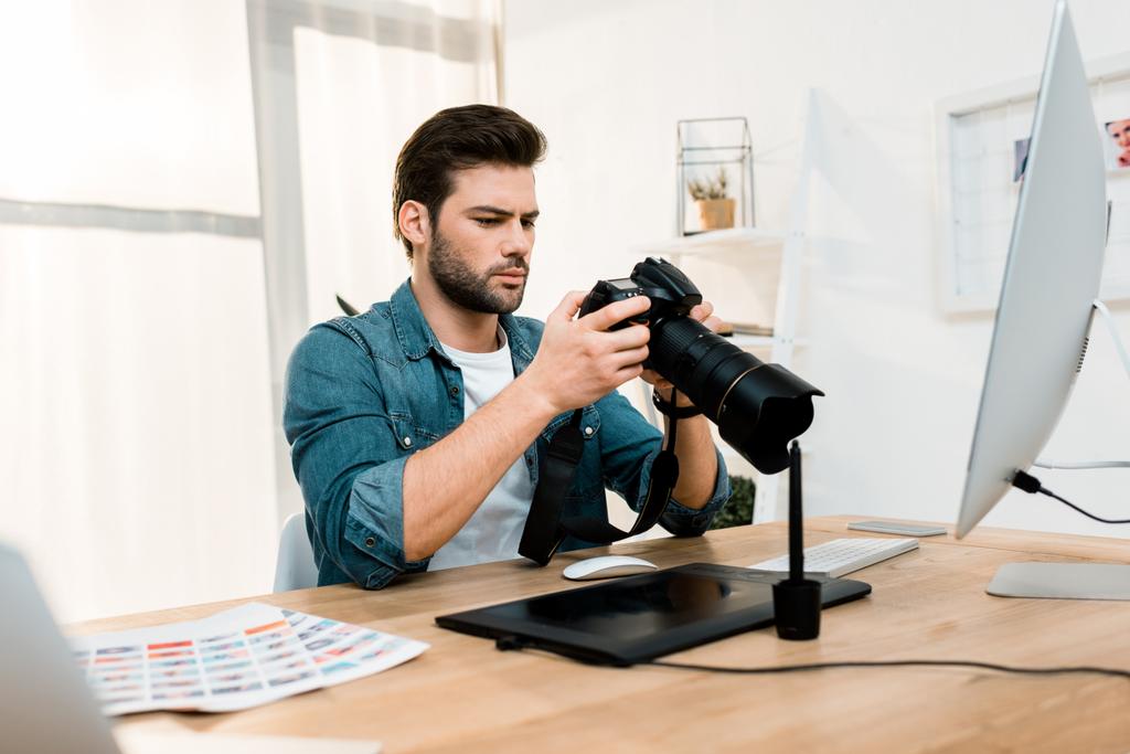 yakışıklı profesyonel genç fotoğrafçı işyerinde kamera kullanarak   - Fotoğraf, Görsel