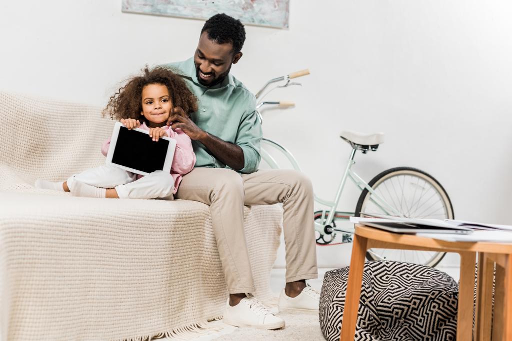 afro-americanos padre e hija usando digital tablet y sentado en sofá
 - Foto, Imagen