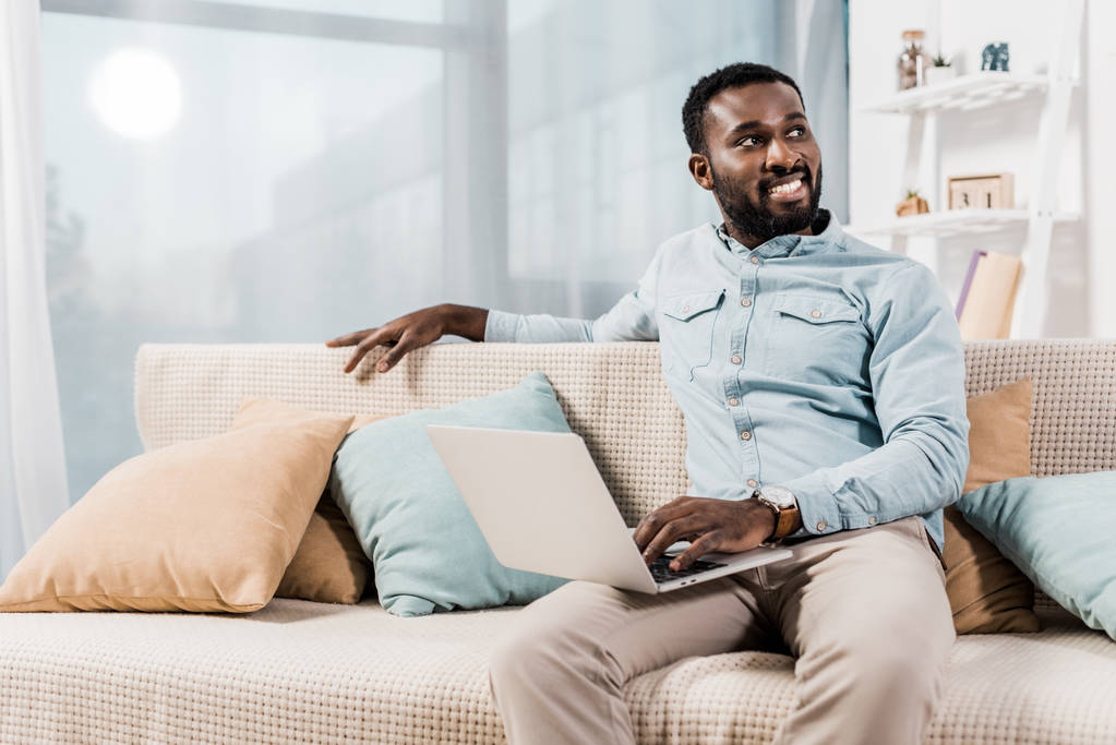 Αφρικανική αμερικανική freelancer κάθεται στον καναπέ στο σαλόνι και αναζητούν μακριά - Φωτογραφία, εικόνα