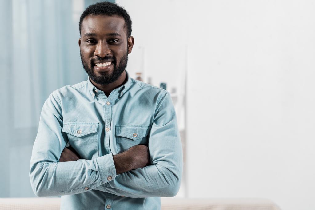 Αφρικανική αμερικανική άνθρωπος βλέπει κάμερα και χαμογελά στο σαλόνι - Φωτογραφία, εικόνα
