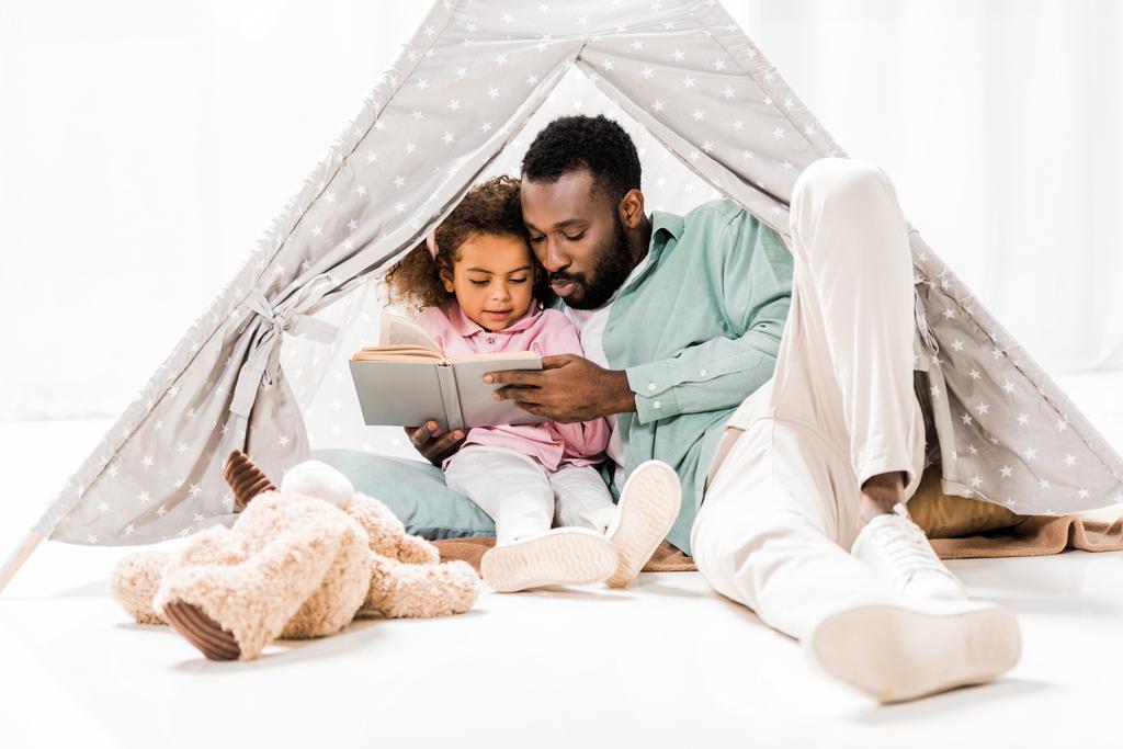 africano americano uomo e figlia lettura libro in salotto
 - Foto, immagini