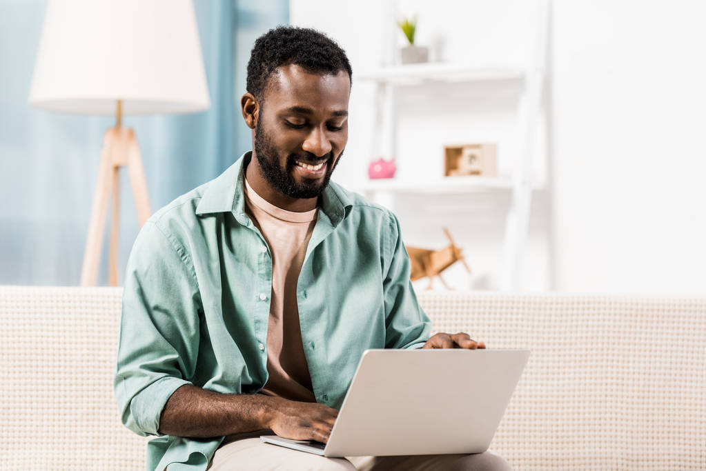 афроамериканець людиною, що працюють на ноутбуці у вітальні - Фото, зображення