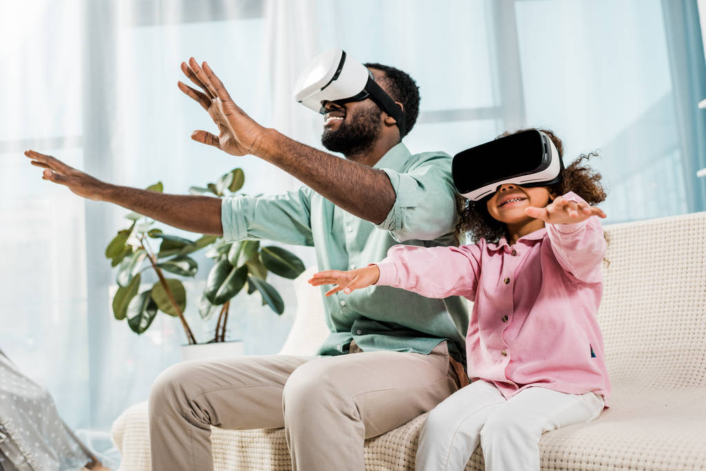padre e hija afroamericanos usando gafas de realidad virtual y sonriendo en la sala de estar
 - Foto, imagen