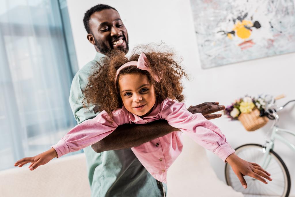 Afro-Amerikaanse vader spelen met dochter in de woonkamer - Foto, afbeelding