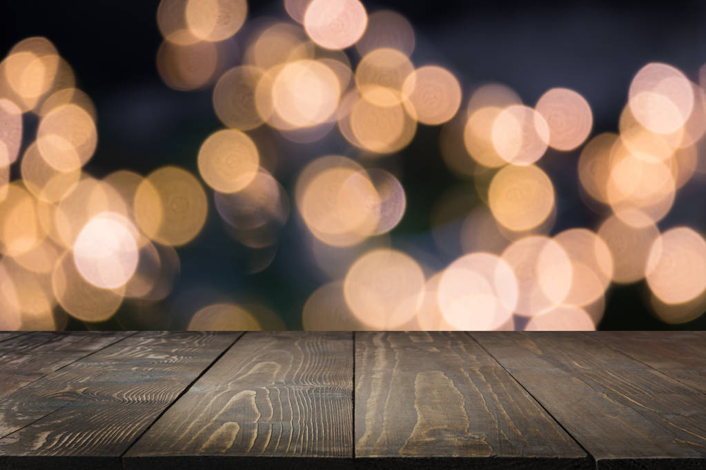 Guirnalda de oro borrosa y mesa de madera como primer plano. Imagen para mostrar o montar sus productos navideños
. - Foto, Imagen