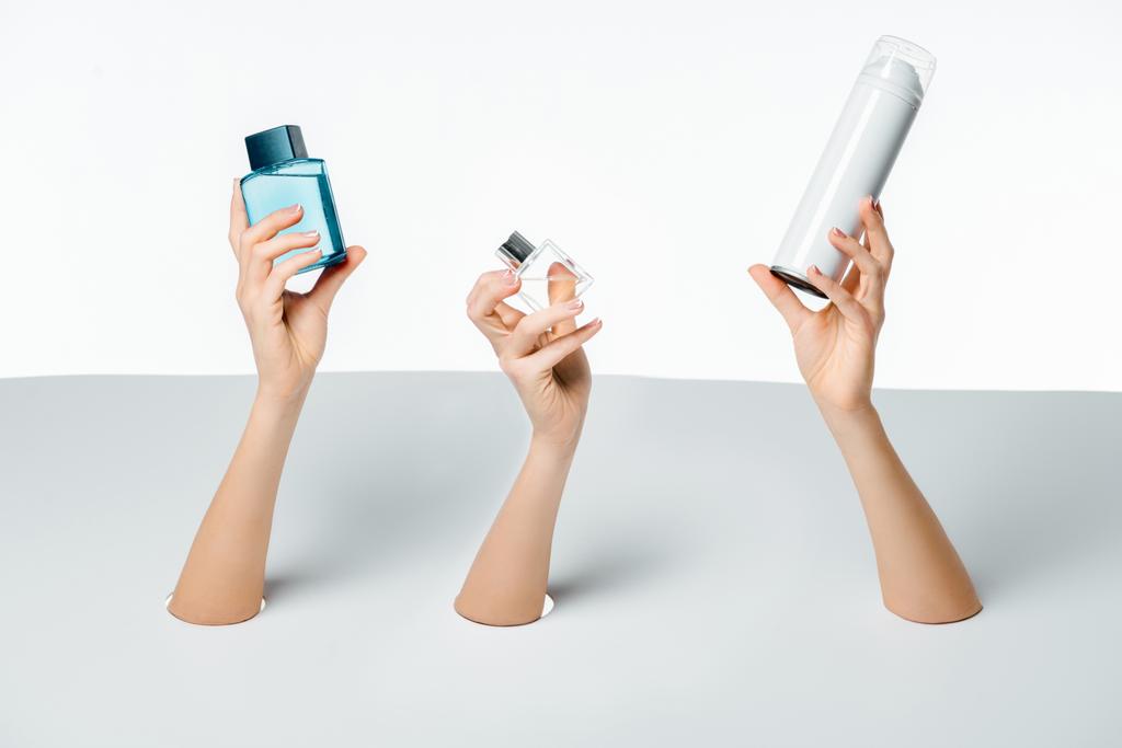 cropped shot of female hands holding perfumes through holes on white - Photo, Image