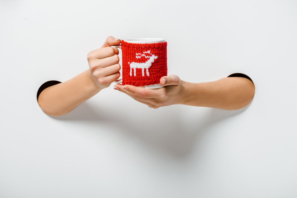 白の穴を通して鹿飾られて一杯のコーヒーを保持している女性のトリミングされた画像 - 写真・画像