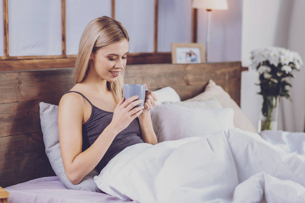 hübsche junge Frau trinkt Kaffee im Bett - Foto, Bild