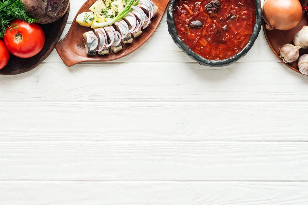 sopa de beterraba tradicional, arenque e ingredientes em fundo de madeira branca com espaço de cópia
 - Foto, Imagem