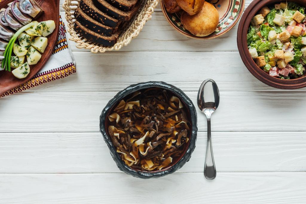 Widok z góry smaczne tradycyjne zupa grzybowa, łyżka i dania całego na białym tle drewnianych - Zdjęcie, obraz