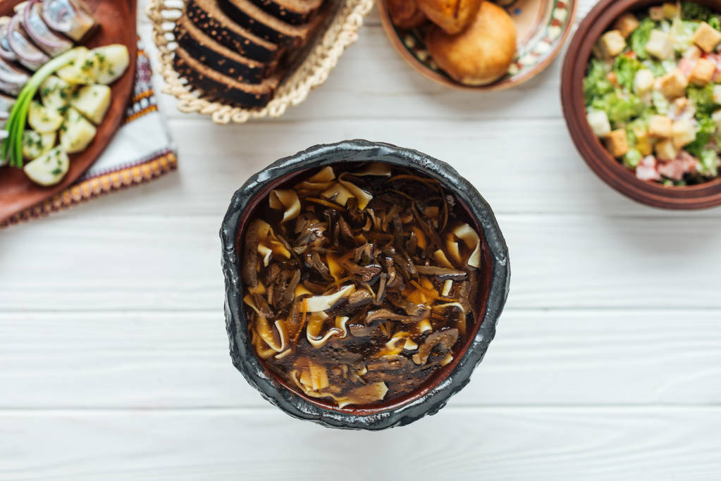 vista dall'alto di deliziosa zuppa di funghi tradizionali e piatti intorno su sfondo di legno bianco
 - Foto, immagini