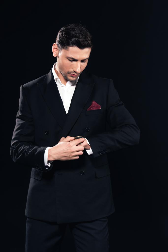vážný muž v obleku uvedení na watch izolované na černém - Fotografie, Obrázek