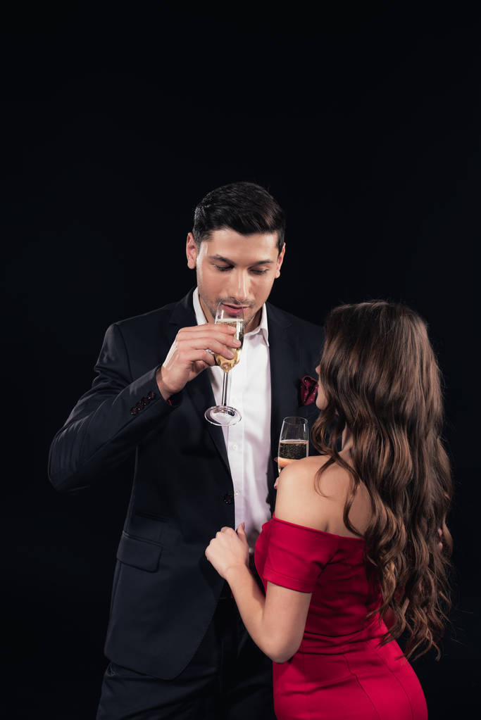 νεαρό ζευγάρι στην επίσημη ένδυση πίνοντας σαμπάνια που απομονώνονται σε μαύρο - Φωτογραφία, εικόνα