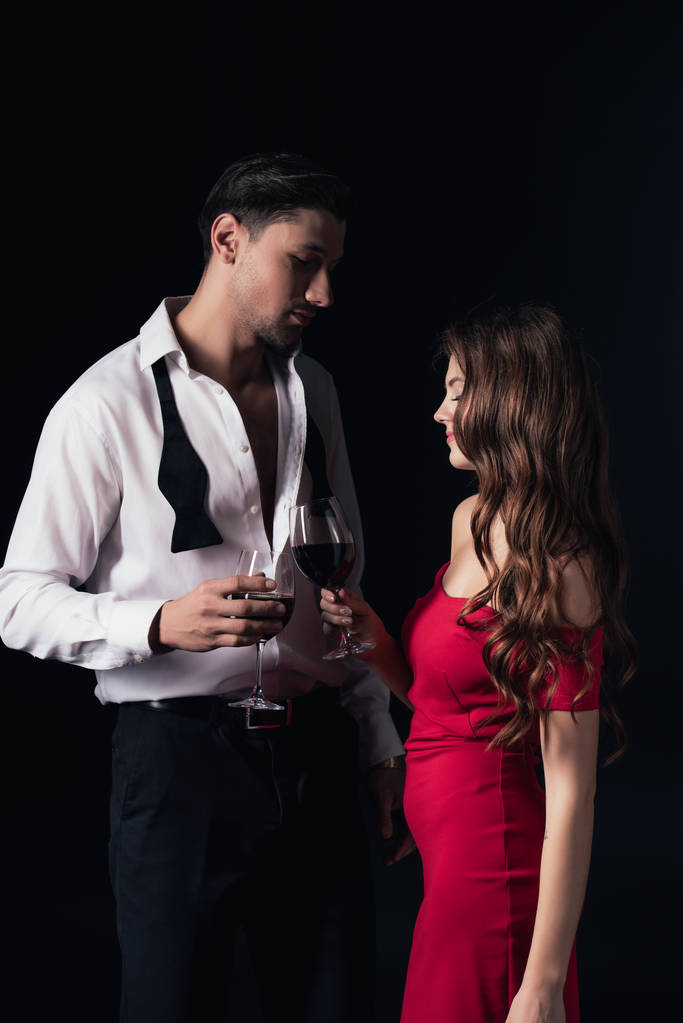 beautiful couple clinking red wine glasses isolated on black - Photo, Image