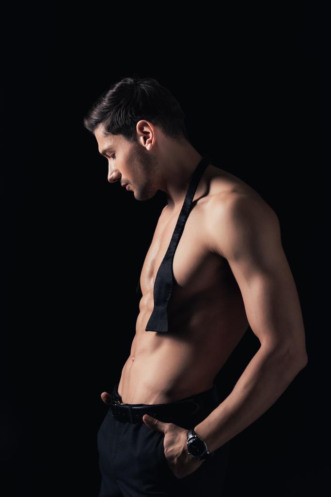 handsome shirtless man with hands in pockets posing isolated on black - Photo, Image