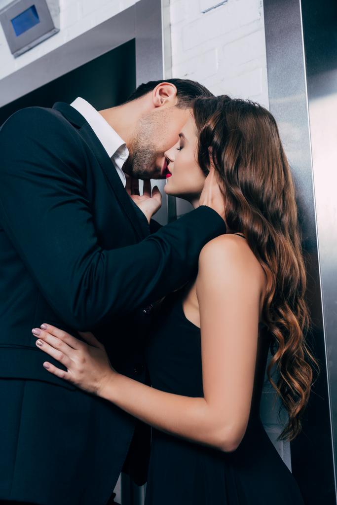 homem de terno apaixonadamente beijando bela mulher perto do elevador
 - Foto, Imagem