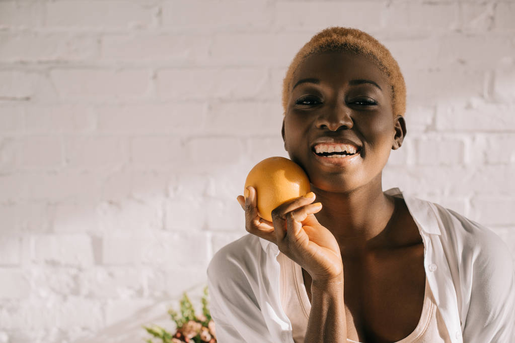 kısa saçlı turuncu holding neşeli Afrikalı-Amerikalı kadın - Fotoğraf, Görsel