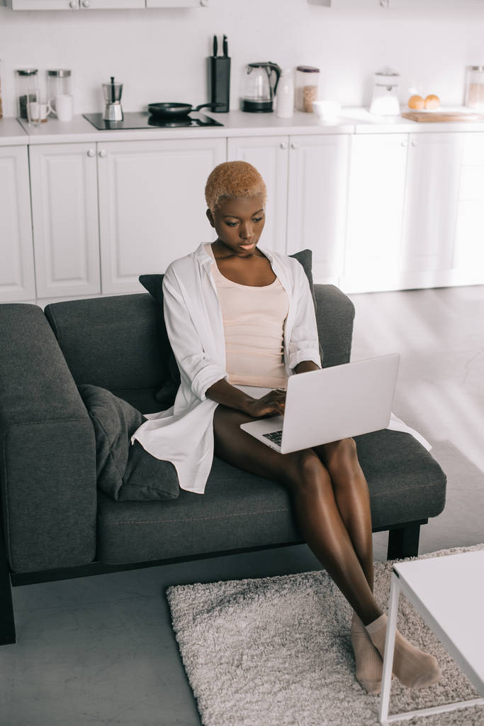 mujer afroamericana centrada escribiendo en el ordenador portátil en la sala de estar
  - Foto, imagen