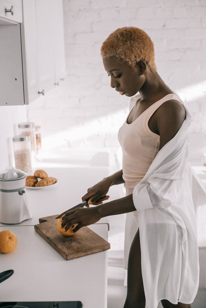 kaunis afrikkalainen amerikkalainen nainen leikkaamalla oranssi leikkuulauta
 - Valokuva, kuva