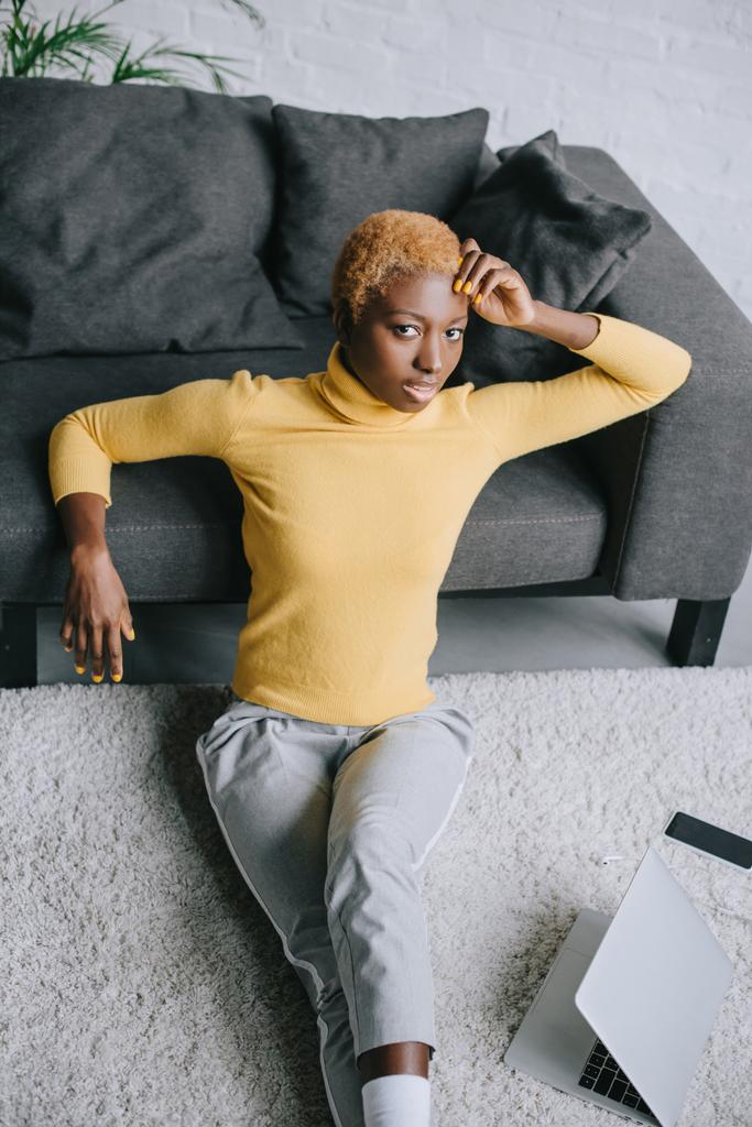 привлекательная африканская американка, сидящая на ковре в гостиной
 - Фото, изображение