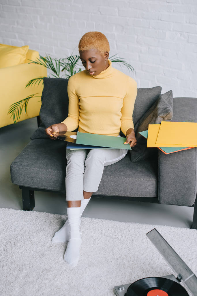 mujer afroamericana pensativa sentada con discos de vinilo en la sala de estar
 - Foto, Imagen