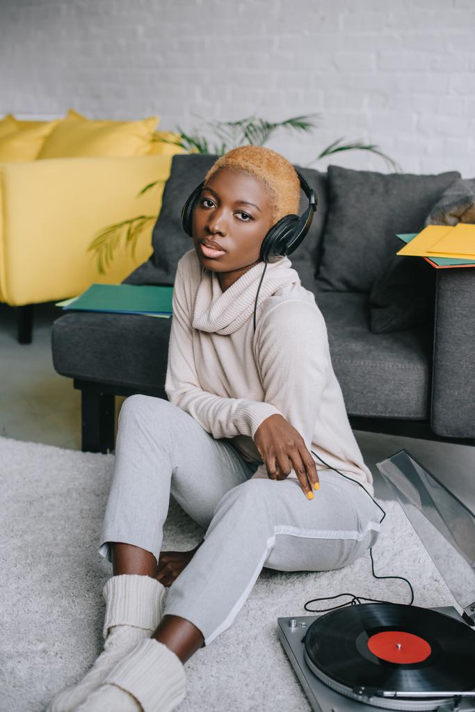 african american woman sitting on carpet and listening music in headphones - Photo, Image