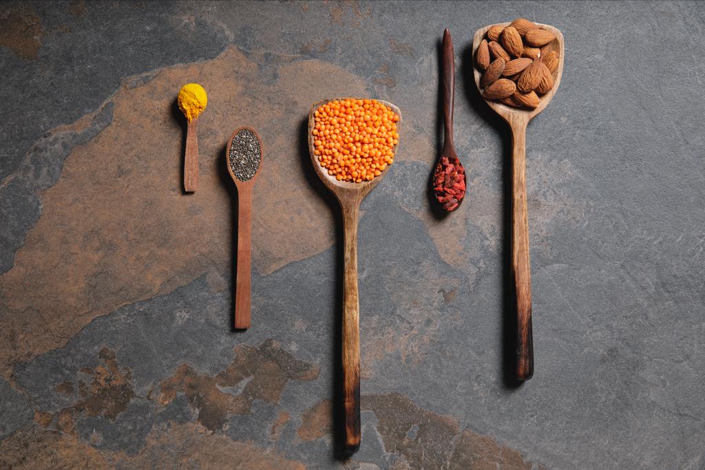 top view of arranged wooden spoons with superfoods, red lentils and turmeric on table - Photo, Image