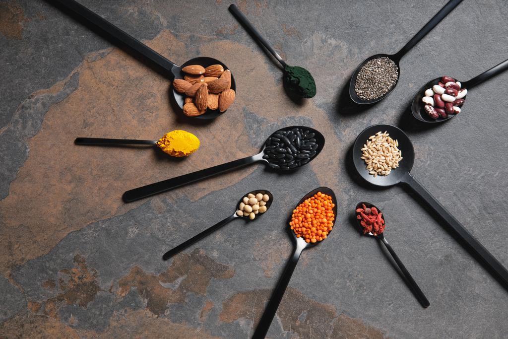 puesta plana de cucharas con superalimentos, legumbres y granos en la mesa
 - Foto, imagen