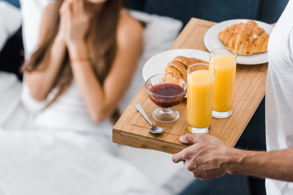 cropped view of man holding wooden tray with orange juice and croissants - Photo, Image