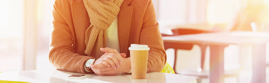 oříznutý pohled na muže, který seděl u stolu s jednorázovými cup v kavárně - Fotografie, Obrázek