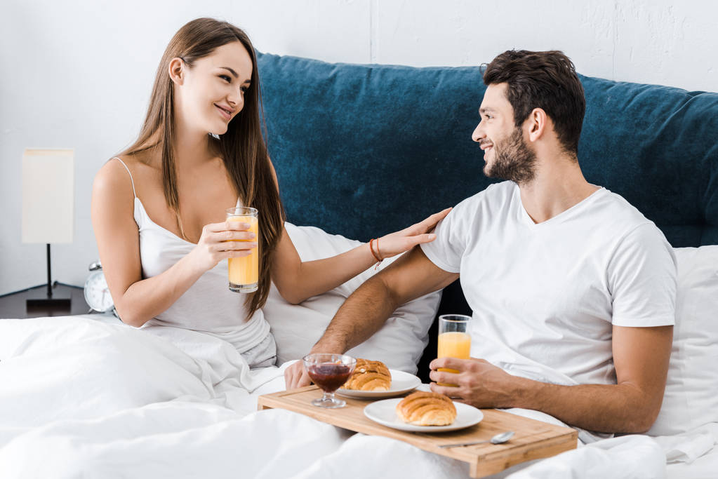 молода усміхнена пара снідає в ліжку
  - Фото, зображення