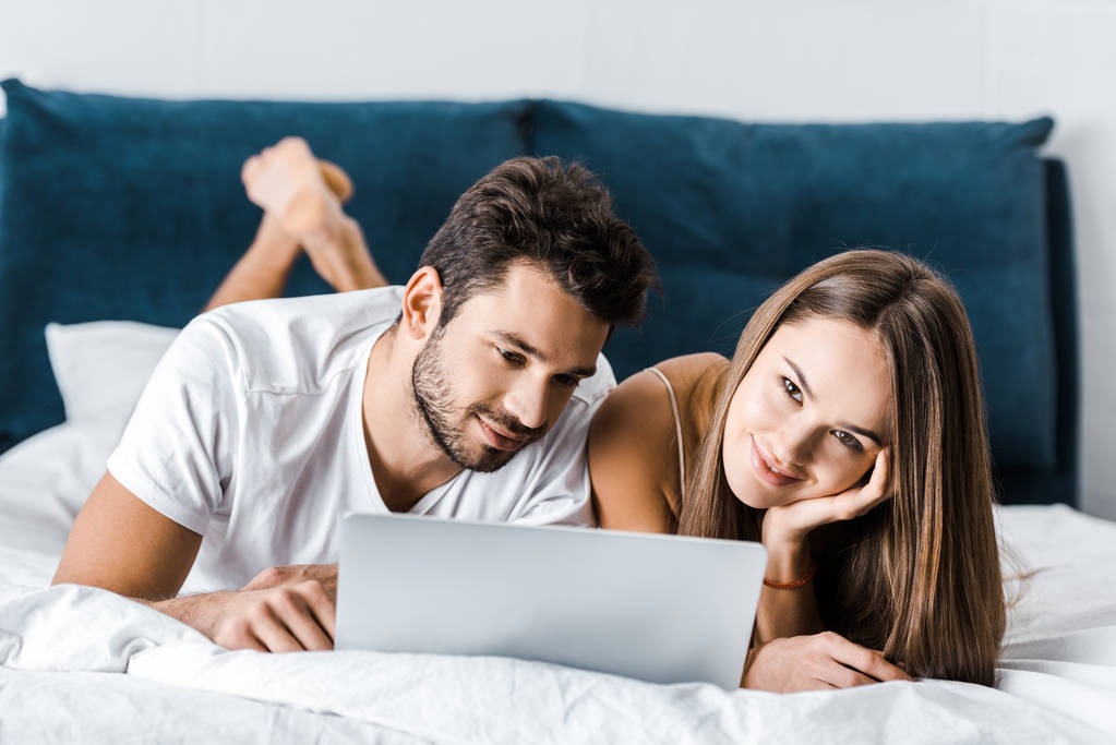 young couple lying in bed and using laptop - Photo, Image